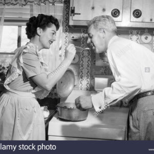 1950-femme-au-foyer-dans-la-cuisine-apres-avoir-mari-gouter-la-nourriture-sur-cuisiniere-cmr82y